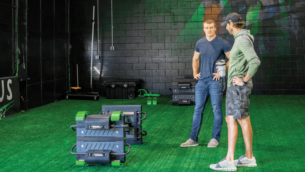 Two Athletes Standing near FlipSled on Turf